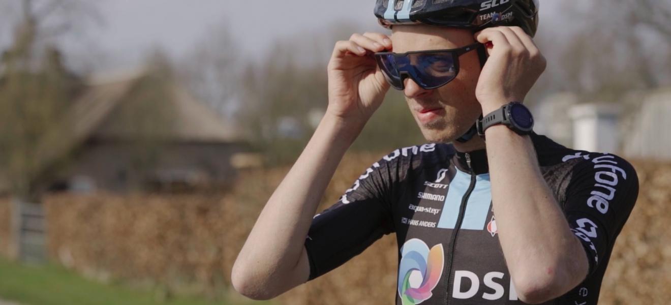 Professional cyclist putting on helmet and sunglasses.