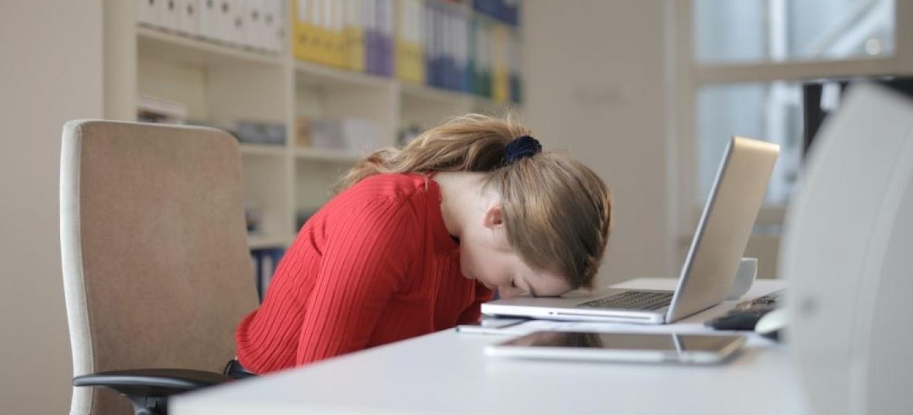 A woman with her head down on her laptop, looking frustrated