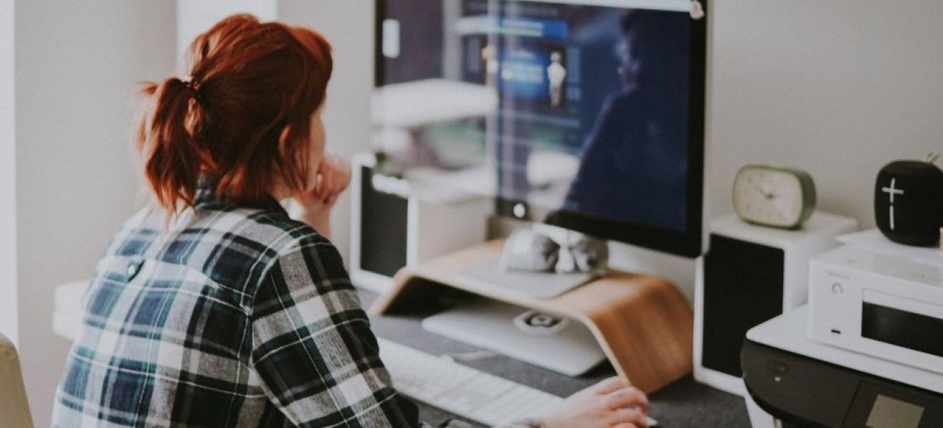 A woman working from home with a large monitor