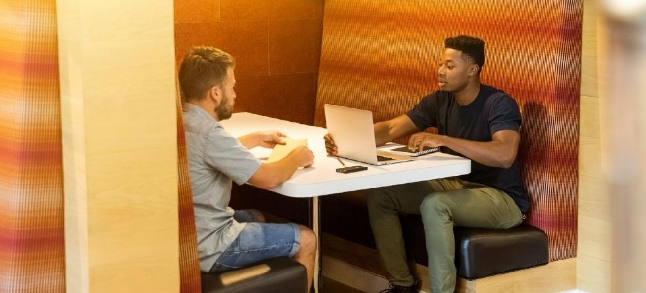 Two men in a working hub using a laptop