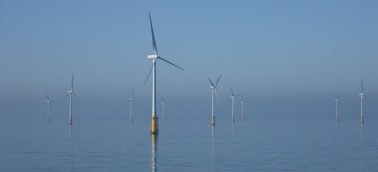 Wind turbines offshore with a blue sky and calm sea