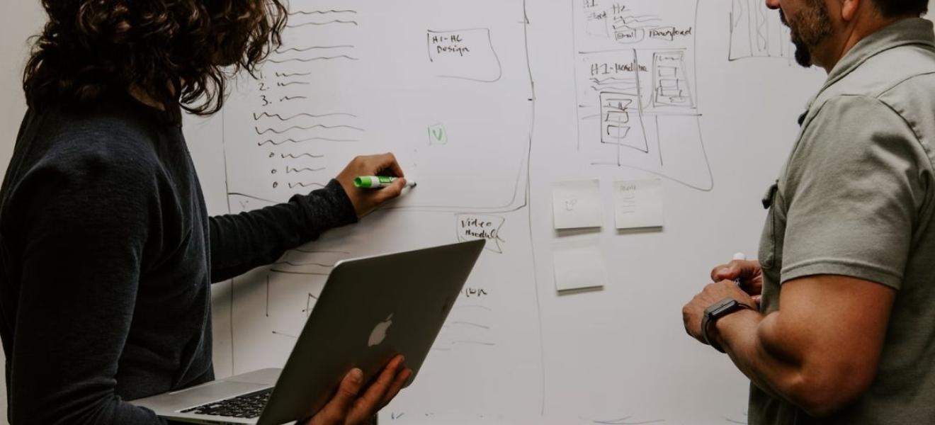 Two people developing a strategy at a whiteboard Two people developing a strategy at a whiteboard