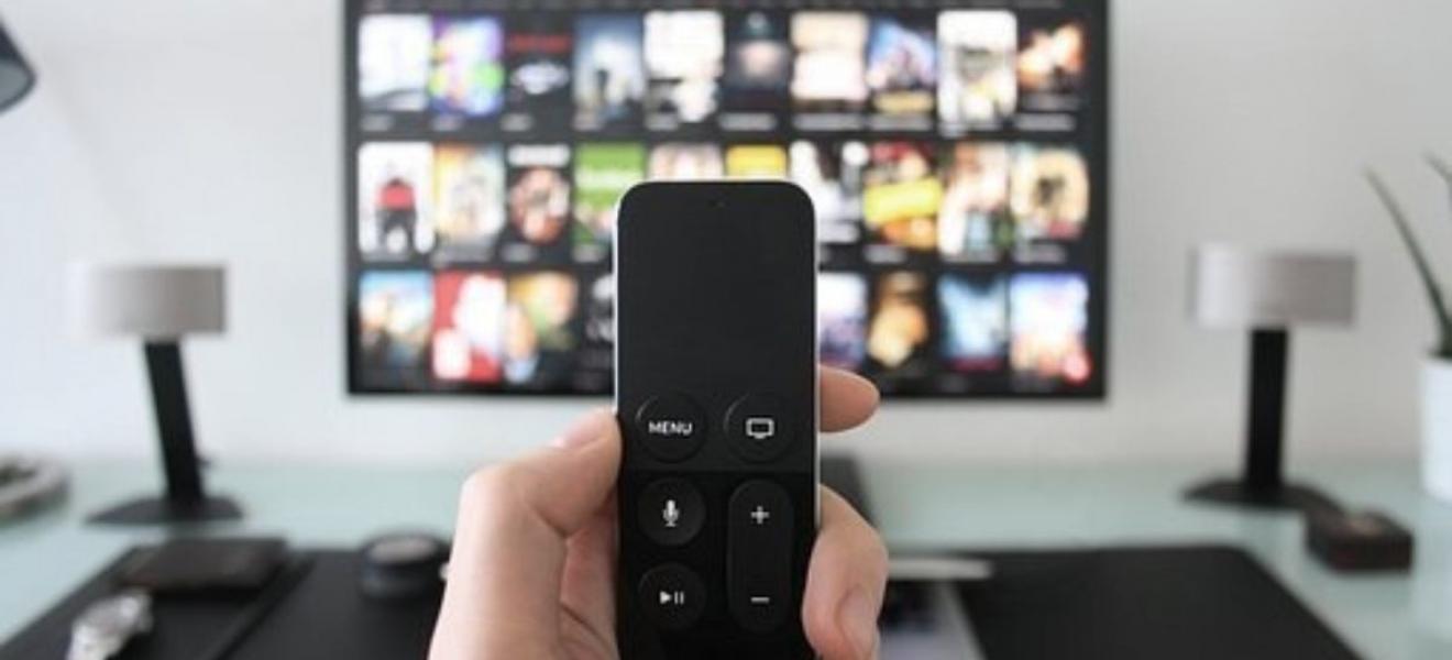 Someone using a remote control to interact with their television Someone using a remote control to interact with their television