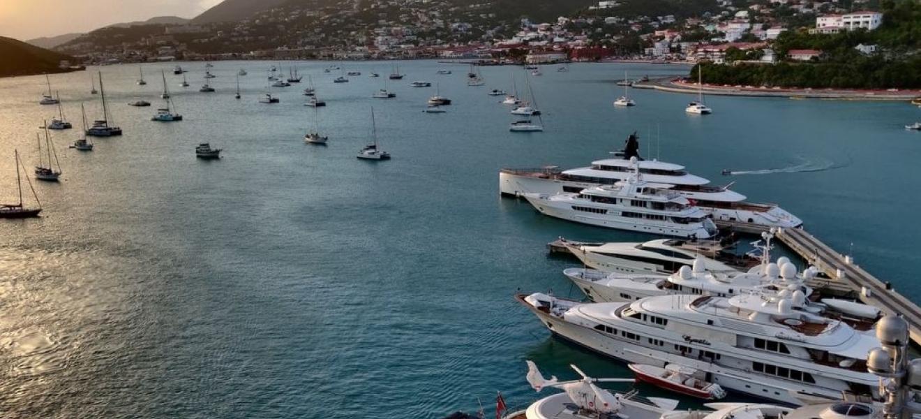 sunset, aquamarine sea and five yachts in the forefront, with smaller boats dotting the horizon 