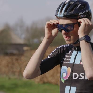 Professional cyclist putting on helmet and sunglasses.