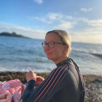 Emily Barrett in a wetsuit with the water in Plymouth behind her