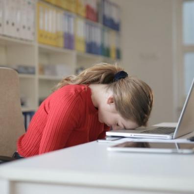 A woman with her head down on her laptop, looking frustrated