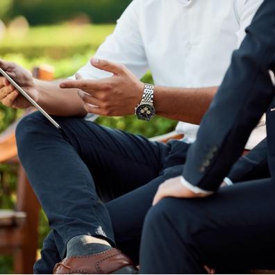 Two people using a tablet outdoors on a bench