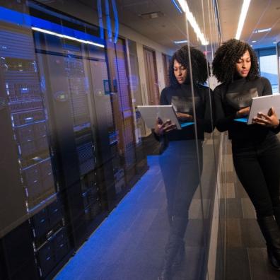 A woman using a laptop next to a large server room