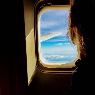 A girl looking out the window of a plane