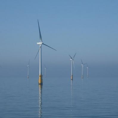 Wind turbines offshore with a blue sky and calm sea