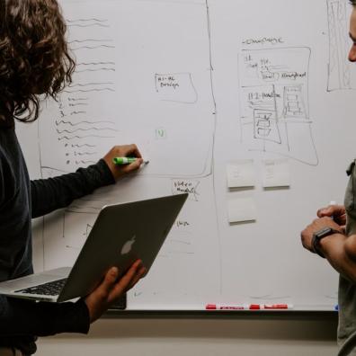 Two people developing a strategy at a whiteboard