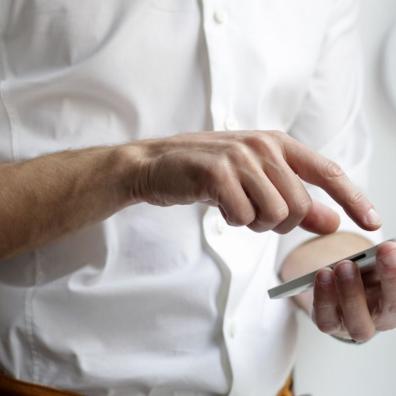 A man wearing a white shirt, using a mobile smartphone