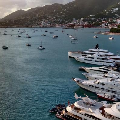 sunset, aquamarine sea and five yachts in the forefront, with smaller boats dotting the horizon 